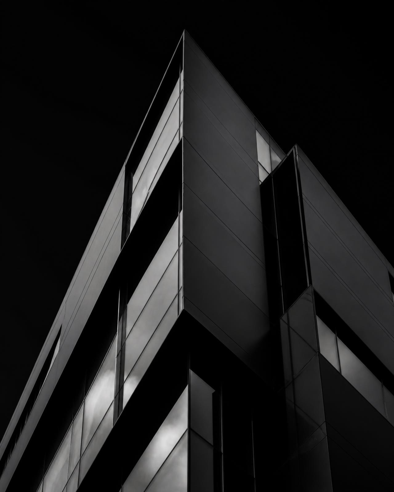 Mørk geometrisk arkitektur med skarpe flader i stål og glas